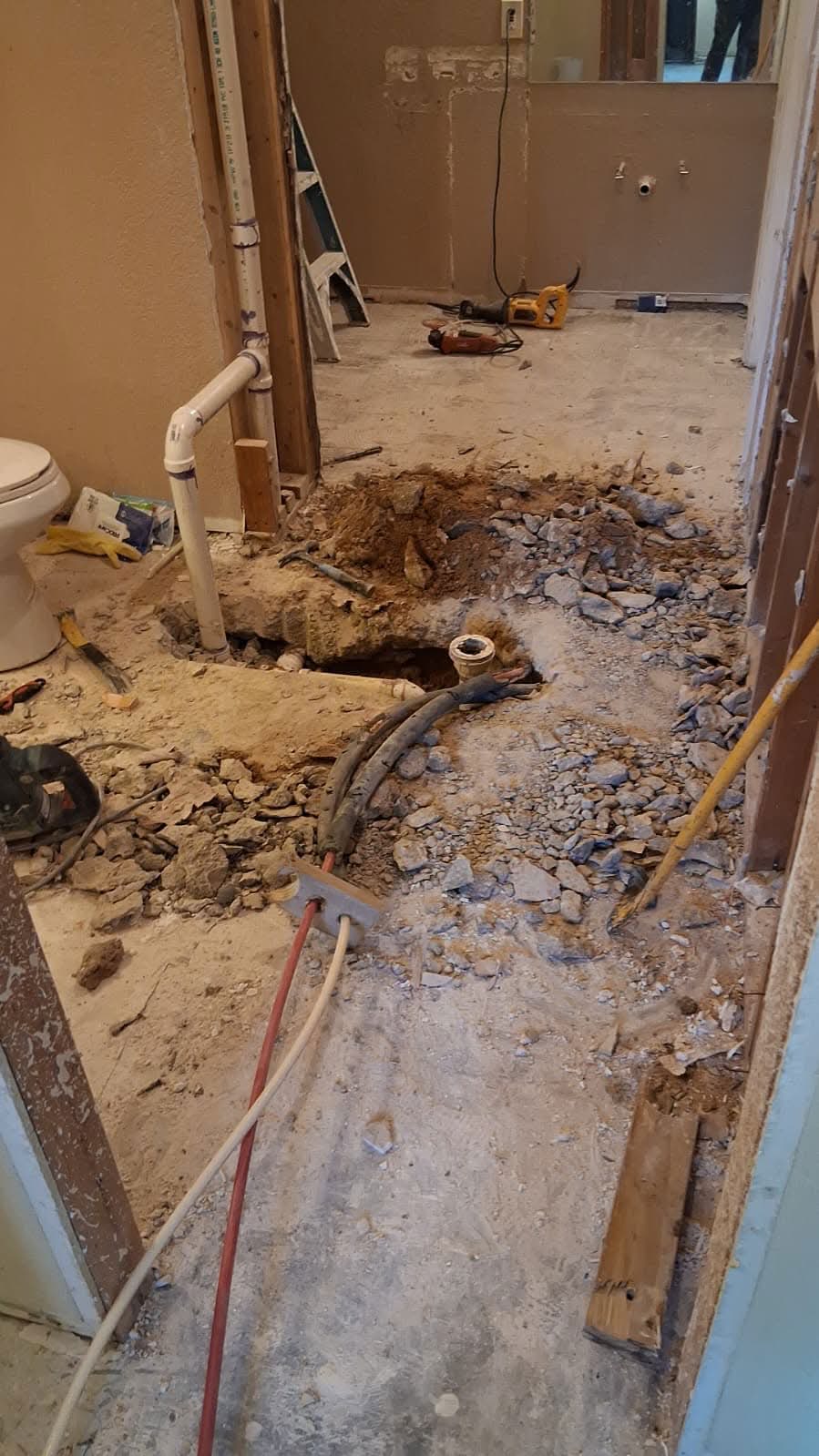 Bathroom floor jackhammered open to replace failed under-slab plumbing during a Keyheart renovation