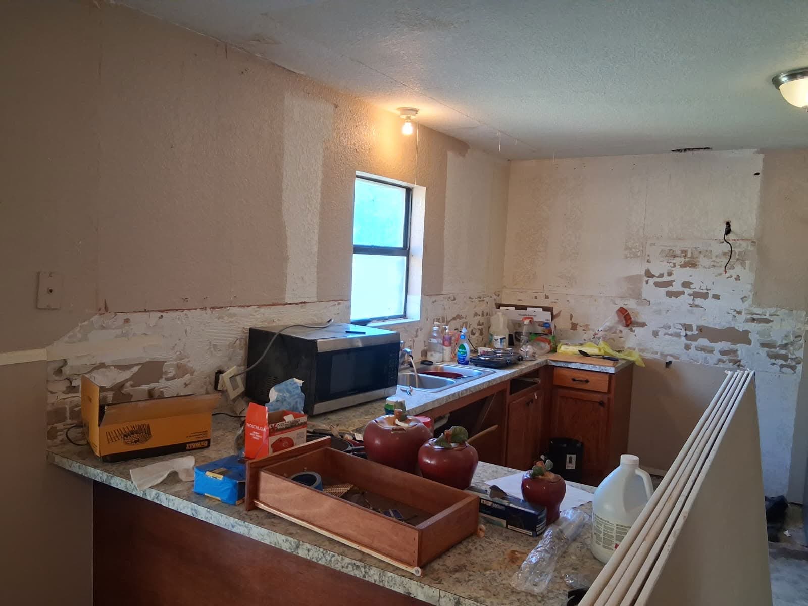 Kitchen mid-demolition during a Keyheart renovation, with the backsplash stripped and cabinets partially removed